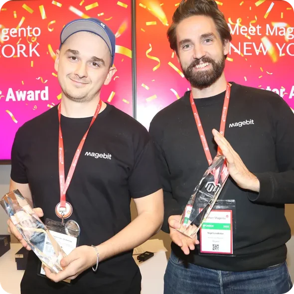 Two men smiling and holding awards, wearing black Magebit shirts with red lanyards.